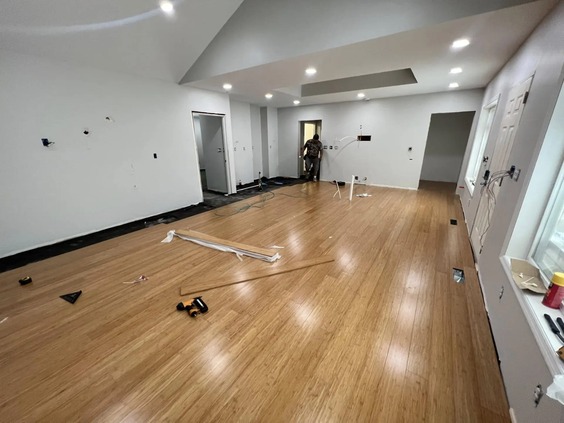Large open room with newly installed hardwood plank flooring during a remodel