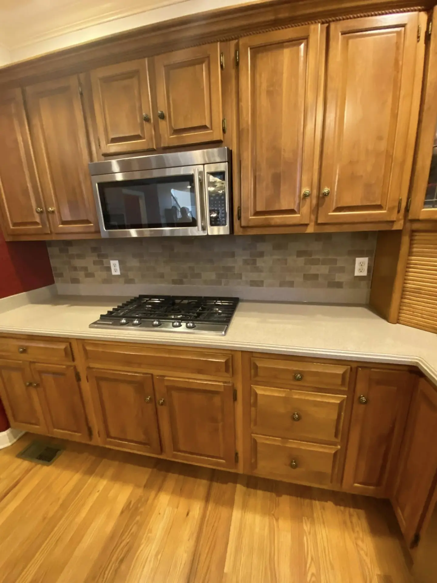 Kitchen with wood cabinets, stone backsplash and solid surface counters