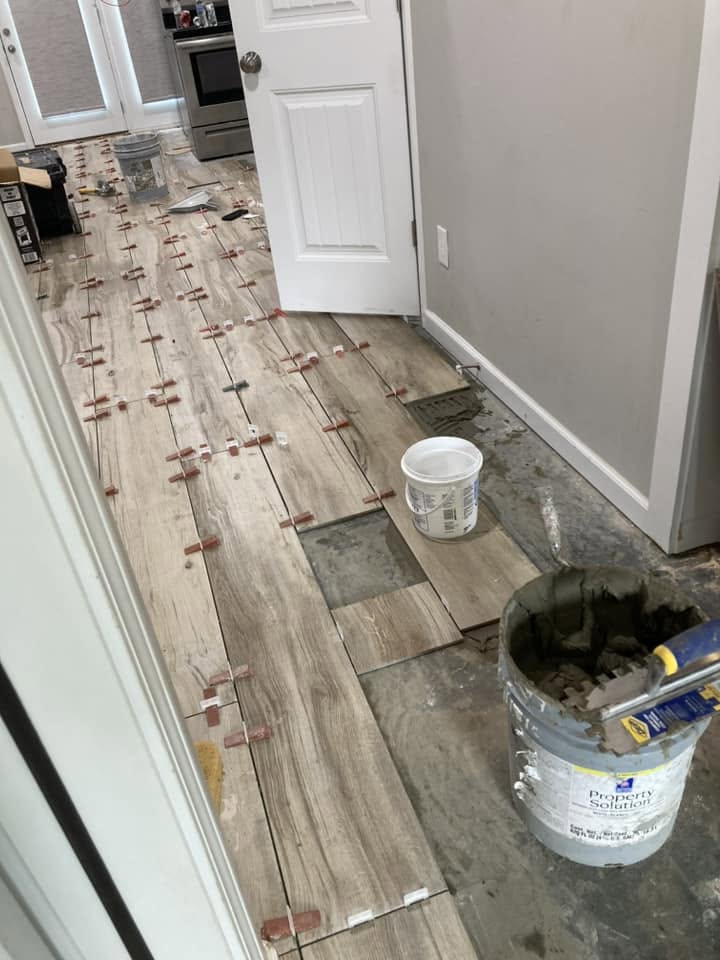 Wood-look tile being installed at a kitchen entry with spacers and mortar