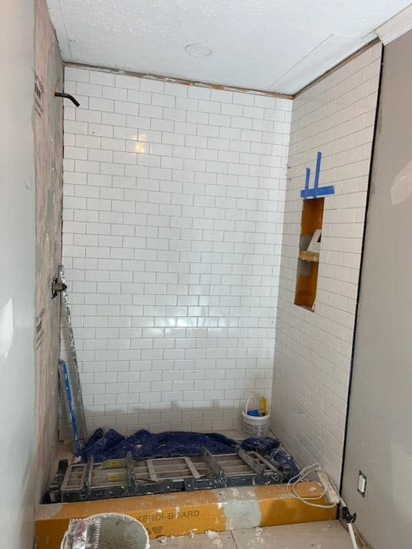 Shower tiled with white subway tile during installation