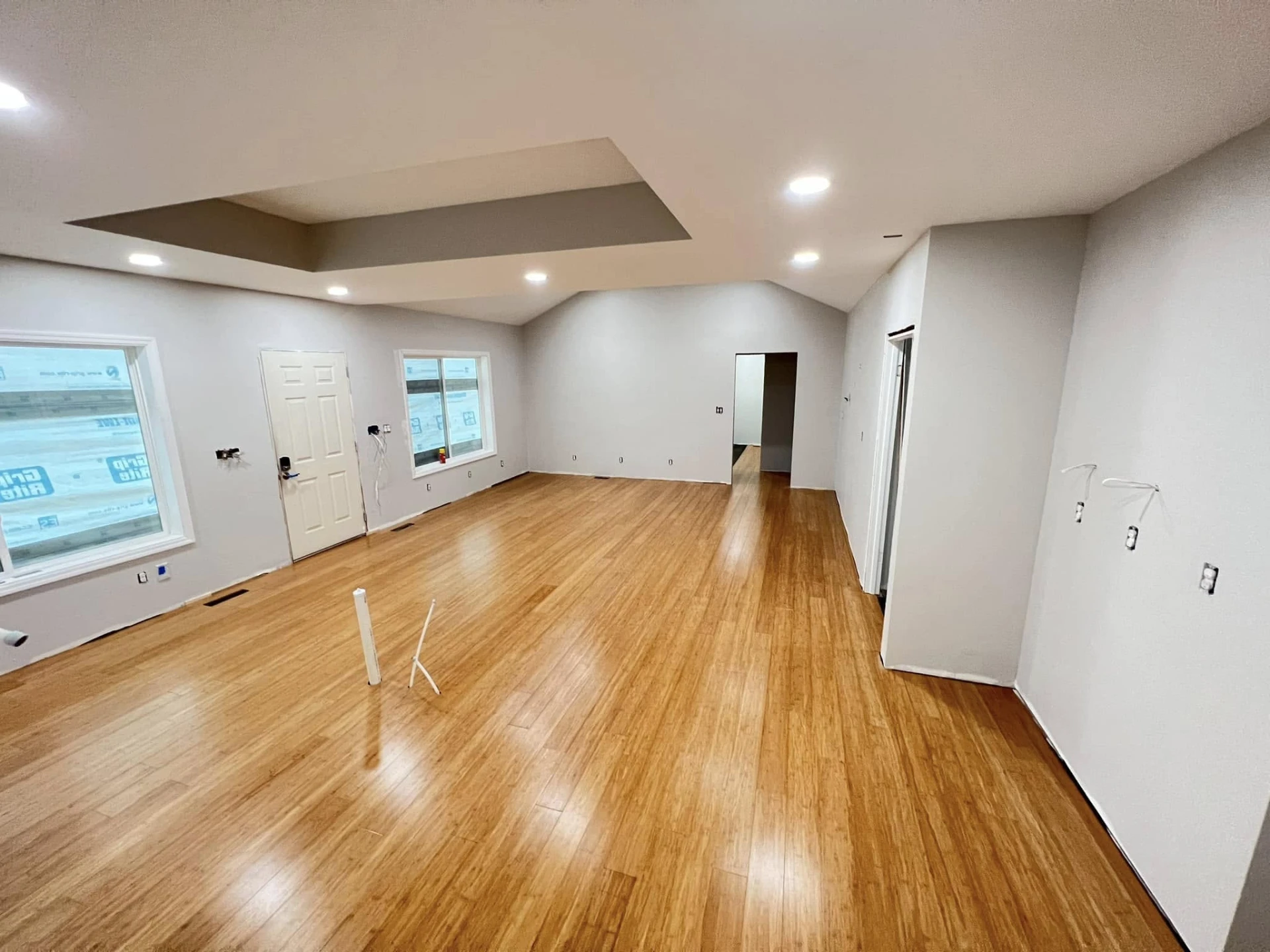 Finished open living space with bamboo hardwood floors and a tray ceiling