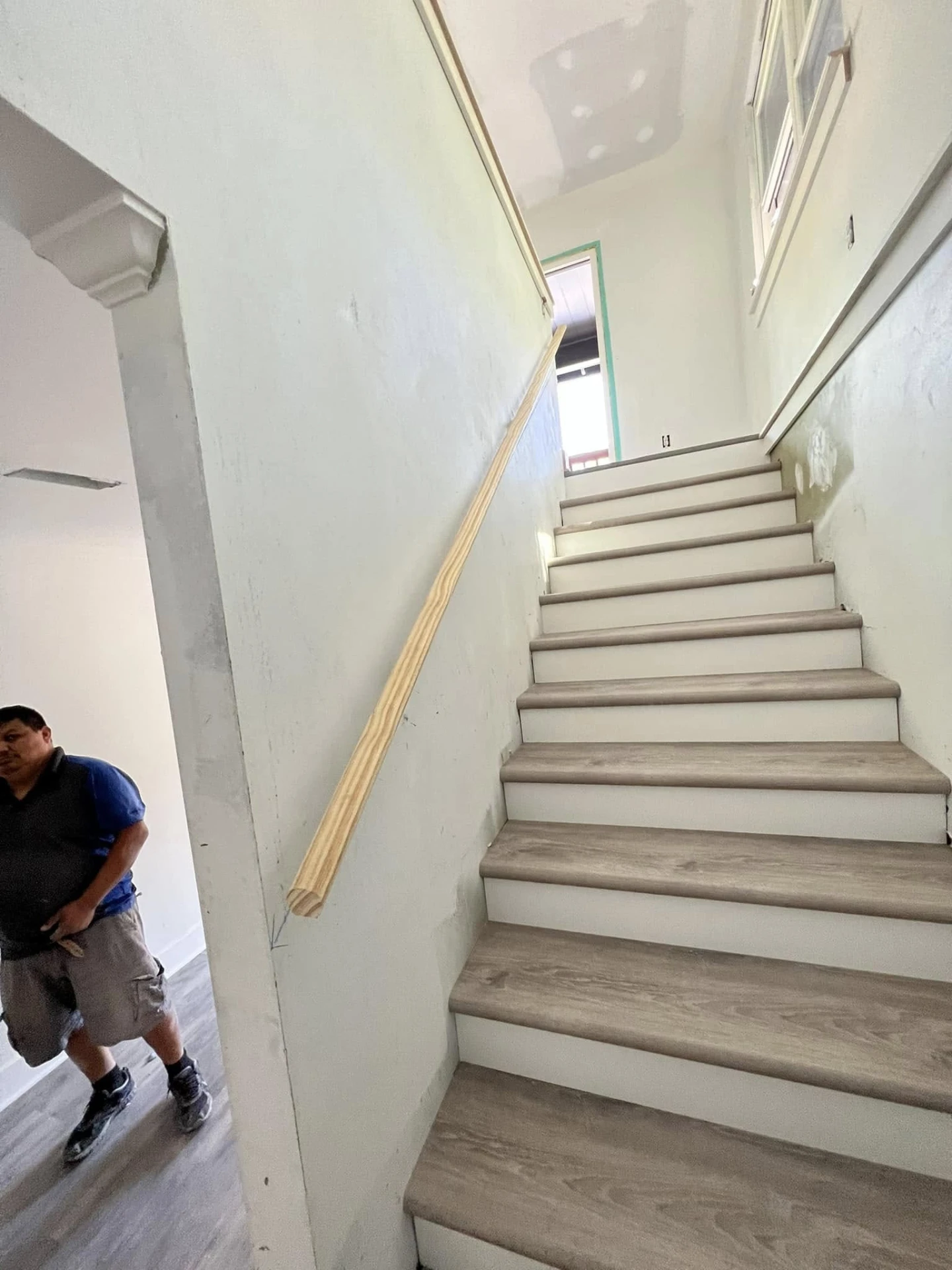 Stairway with new treads, white risers and a wood handrail installed